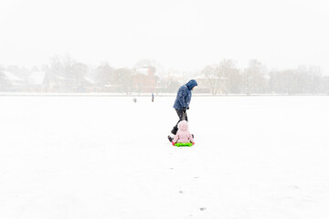 a man is walking with kid on sled