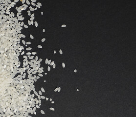 Scattered white uncooked rice in cereals on a black background