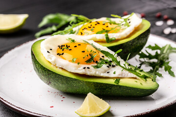 Fried eggs in avocado with fresh herbs and spices. Avocado stuffed with eggs. Delicious breakfast or snack on a light background, top view