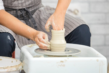 Hands of a woman potter sculpt a jug of clay on a potter's wheel