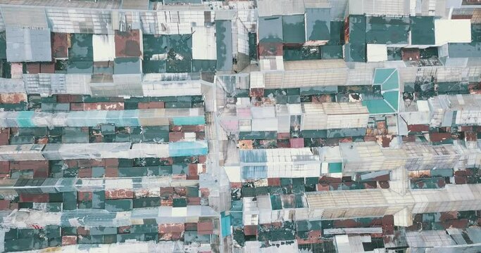 Aerial top-down view high altitude of slum a heavily populated urban informal settlement characterized by substandard housing and squalor poor living conditions streets and rusty metal home roof tops