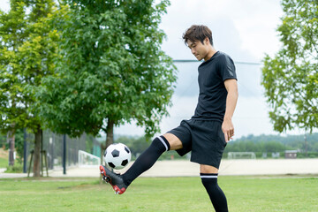 公園でサッカーをする若い男性