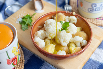 Italy. Vegetarian Potato and Cabbage salad contained in a ceramic bowl, placed on a wooden cutting board with two ceramic jars on the sides and with salt and parsley.