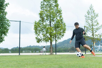 公園でサッカーをする若い男性
