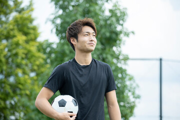 公園でサッカーをする若い男性
