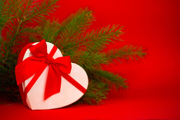 A gift for a loved one in the shape of a heart for Christmas. Gifts for the new year on a festive red background.