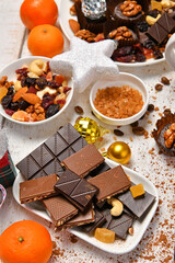 sweet food top view background for merry christmas or new year holiday decoration - chocolate candies, tangerines, cookies on white wood