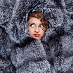 Portrait of a surprised young girl in fur of a silver fox