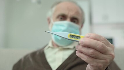 Sad aged man in protective mask showing thermometer, symptoms of fever, virus