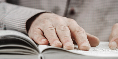 adult man reads interesting book at table in light room