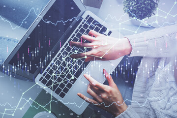 Double exposure of woman hands working on computer and forex chart hologram drawing. Top View. Financial analysis concept.