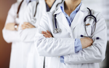 Group of modern doctors standing as a team with arms crossed in sunny hospital and ready to help patients. Medical help, insurance in health care