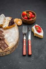 front view cake slices with choco bars and strawberries on dark background biscuit fruit sweet