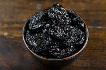 Fresh prunes in wooden bowl. Dried plums.