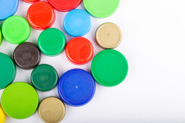 Many multi-colored plastic bottle caps on a white background.
