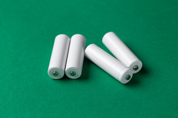 Rechargeable AAA batteries in white on a green background. Place for text.