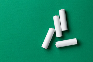 Rechargeable AAA batteries in white on a green background. Place for text.