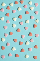 Valentine's day background. Colorful pastel  heart shaped sprinkles on blue background. Sugar sequins cake decor: nonpareils, hundreds and thousands, confetti. Social media likes and online dating.