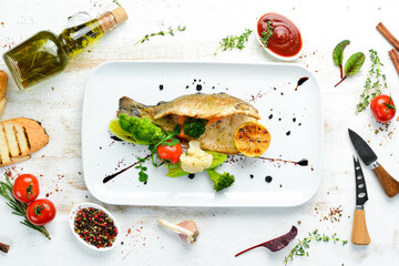 Fototapeta na wymiar Baked trout fillet with vegetables on a plate. Top view. Free copy space.