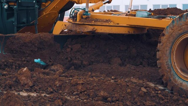 Slow motion close up shot of grader machine moving soil.