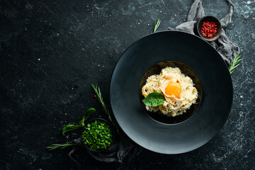 Carbonara pasta with egg and parmesan cheese and basil in a plate on a black stone background. Top view. Rustic style.