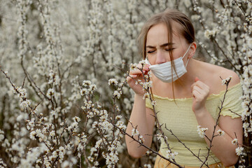 Girl in a medical mask. Girl in the spring among the blooming garden. A girl in a protective...
