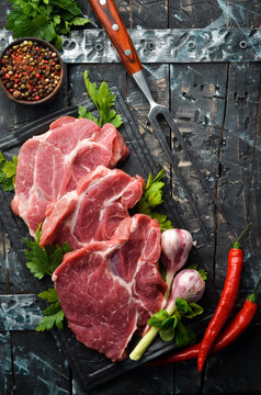Raw veal meat with parsley and spices on the table. Beef steak. Top view. Free space for your text. Rustic style.