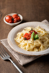 Farfalle pasta in a ceramic plate on a wooden background, selective focus