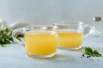 bone broth in a glass cup on a light background, selective focus