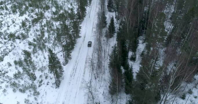 A grey car is driving along a country road. Aerial.