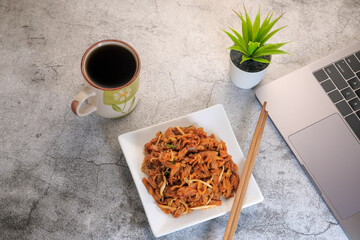 Laptop computer or notebook, char kuew tiaw and cup of coffee on working table with copy space .
