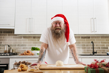 A smiling funny overweigh man in Santa Claus hat with tattooed arms
