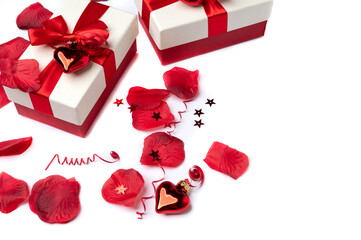 Gift boxes with bows as well as rose petals and a festive envelope on a white