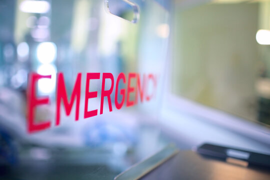 Transparent plastic divider on the reception desk in the hospital admission department with red lettering emergency