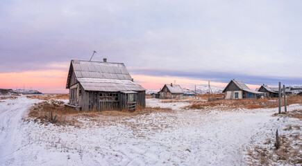 Magical colorful sunset with an old village in the Polar North. view of the winter city of Teriberka.