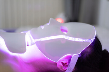 Woman With Led Light Therapy Facial Beauty Mask Photon Therapy. Woman receiving face light therapy...