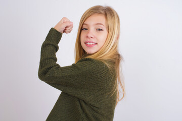 Portrait of powerful cheerful Caucasian kid girl wearing green knitted sweater against white wall 
...