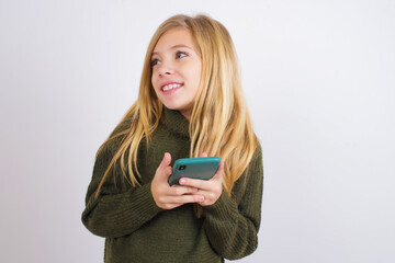 Copyspace photo of Caucasian kid girl wearing green knitted sweater against white wall  stupor with something occurring in social media