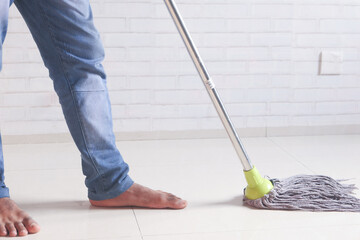 young man cleaning floor with mob 