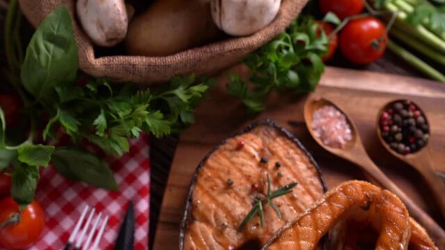 Grilled salmon fish with seasoning and various vegetables on cutting board