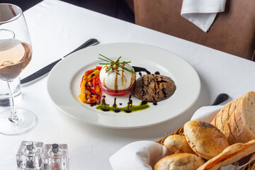 Burrata cheese with vegetables mushroom and light rose wine on a white table in a luxury restaurant