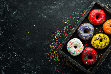 Colored sweet donuts in a wooden box. Top view. Flat Lay.