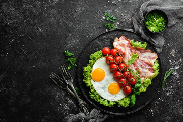 Breakfast. Fried eggs with bacon and cherry tomatoes. Top view. Free space for your text.