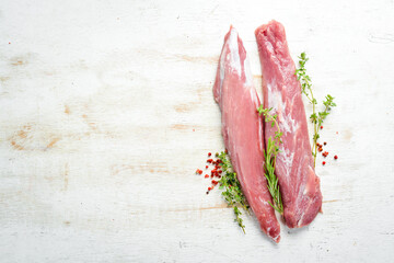Raw pork tenderloin with spices on a white wooden background. Meat. Top view. Rustic style.