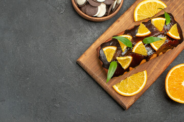 Overhead view of tasty cakes cut lemons with biscuits on cutting board on blackbackground