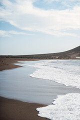 Sandy beach on the Atlantic Ocean. Red Mountain is an extinct volcano. Canary Islands.