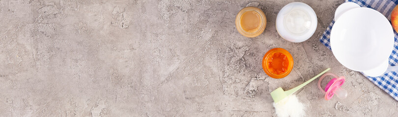 Bowl with vegetables puree and bottle of baby food on gray background. Top view