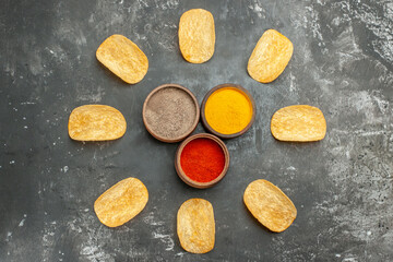 Naklejka premium Homemade potato chips arranged in a circle and mayonnaise ketchup spices on gray background