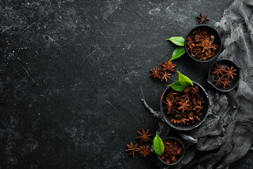 Anise stars in bowls on black stone background. Badian - Indian spices. Top view.