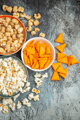 top view different snacks for movie time on a light-dark background cips rusks popcorn